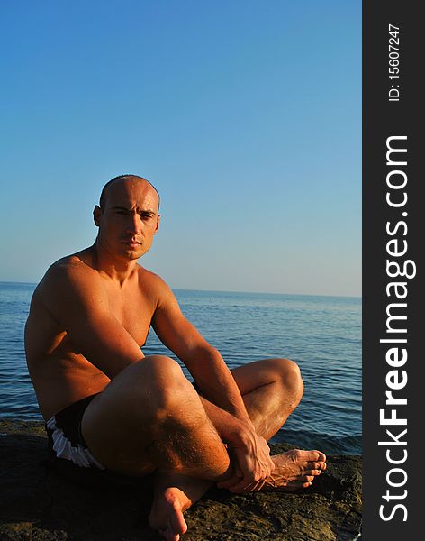 Man sitting on a rock contemplating the sea. Man sitting on a rock contemplating the sea