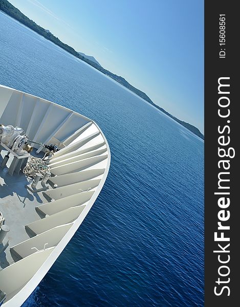 White front of a passenger ship, blue sea and clear sky in background, diagonal composition. White front of a passenger ship, blue sea and clear sky in background, diagonal composition