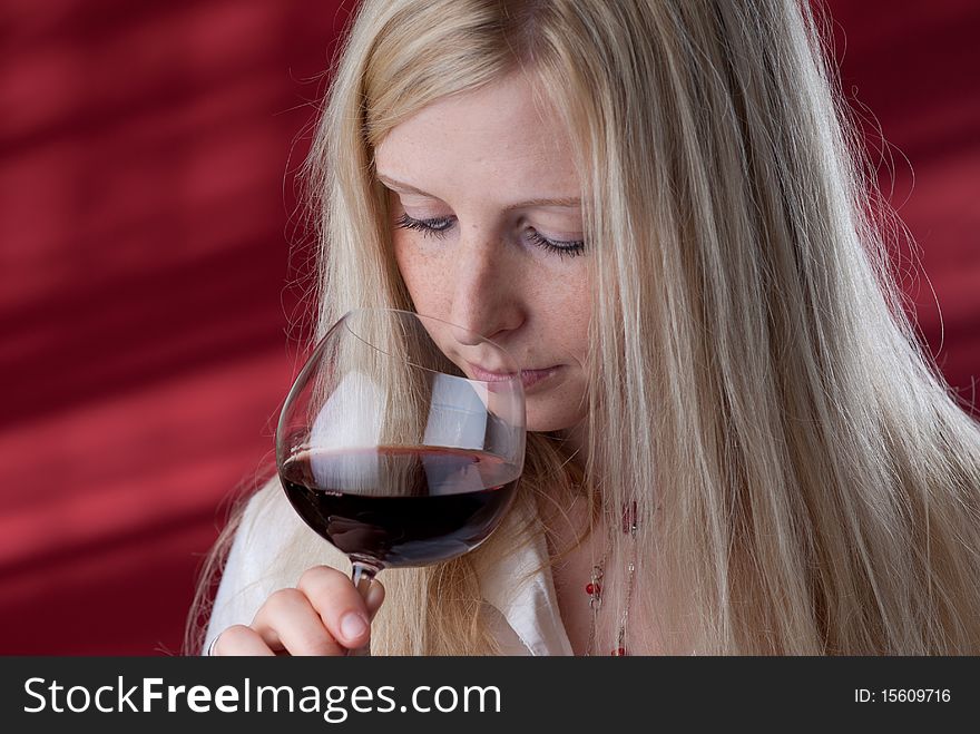 Portrait of a beautiful young woman with a glass of red wine, she is smelling. Portrait of a beautiful young woman with a glass of red wine, she is smelling.