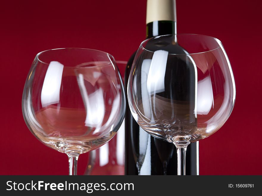 Detail of two wineglasses, red wine bottle and carafe with red background. Detail of two wineglasses, red wine bottle and carafe with red background.