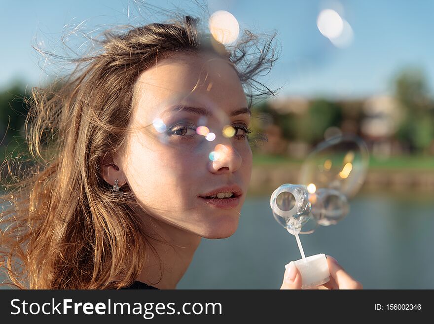 Portrait Of A Young Beautiful Woman In A Dress Blowing Bubbles