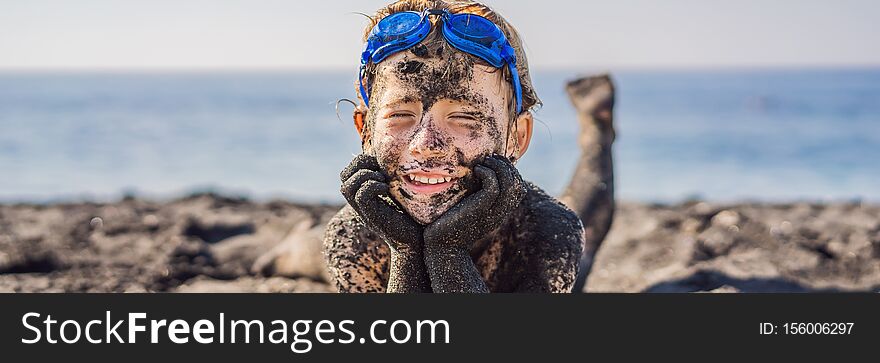 BANNER, LONG FORMAT Black Friday concept. Smiling boy with dirty Black face sitting and playing on black sand sea beach