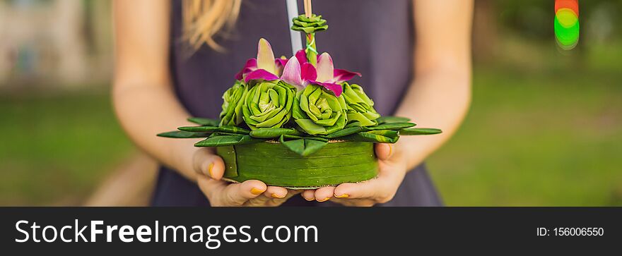 BANNER, LONG FORMAT A female tourist holds the Loy Krathong in her hands and is about to launch it into the water. Loy Krathong festival, People buy flowers and candle to light and float on water to celebrate the Loy Krathong festival in Thailand.