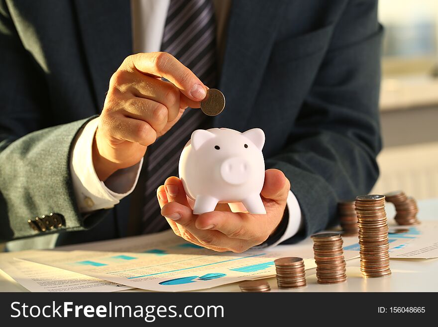 Hand businessman putting pin money into pig. Future needs loan education or mortgage credit spend vacation of dream effective buying financial risk and safety concept