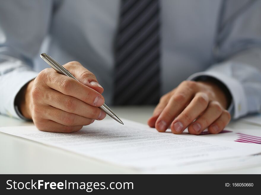 Hand of businessman in suit filling and signing with silver pen partnership agreement form clipped to pad closeup. Management training course, some important document, team leader ambition concept