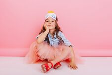 Joyful Little Girl In Tulle Skirt Sitting On White Floor Isolated On Pink Background. Pretty Princess Child With Mask On Royalty Free Stock Photo