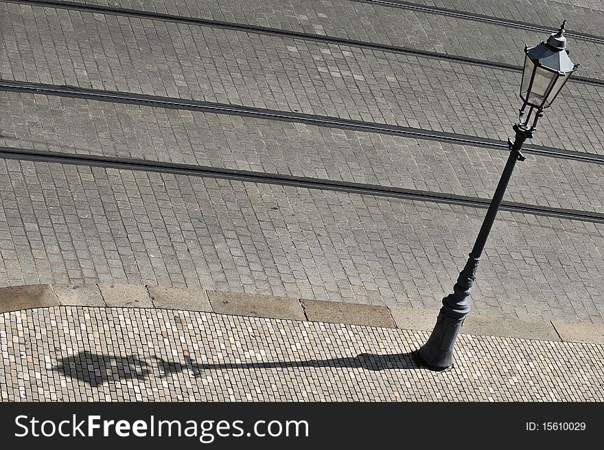Old lamp post with shadow against cobblestone