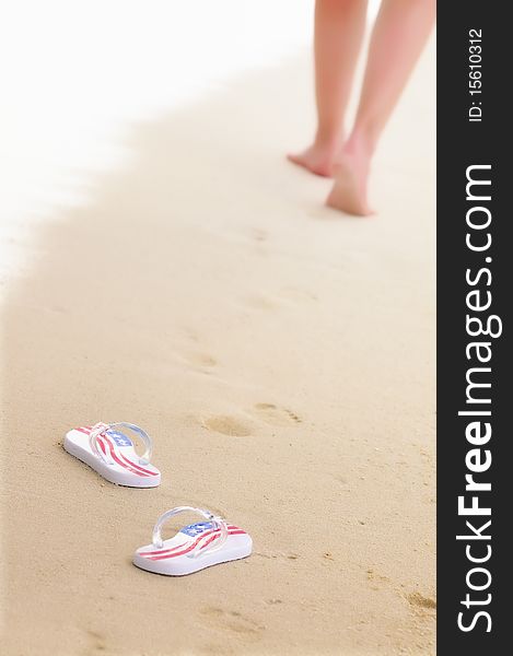 Woman's legs and pair of flip-flops on the beach. Focus on flip-flops. Woman's legs and pair of flip-flops on the beach. Focus on flip-flops.
