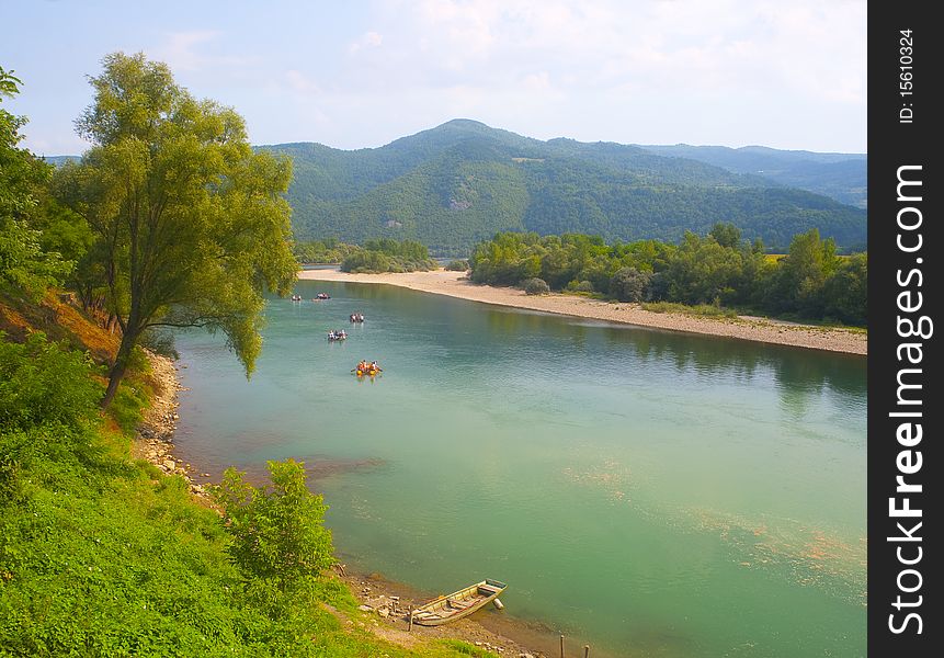 Group of unidentifiable people rafts in the rubber boats on green mountain river. Group of unidentifiable people rafts in the rubber boats on green mountain river.