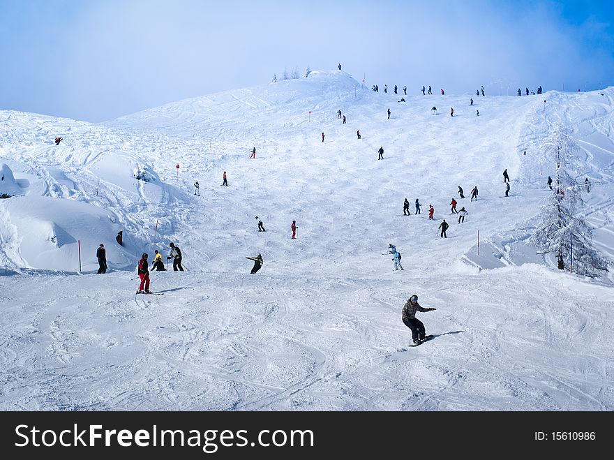 People skiing and snowboarding on an Austrian piste