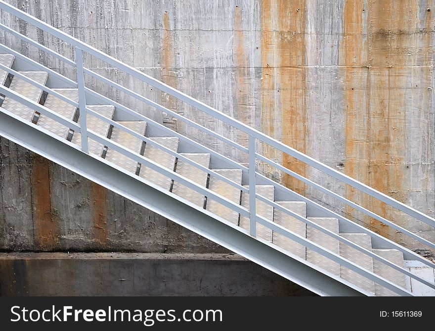 A image of ladder and hand rail, beside wall.