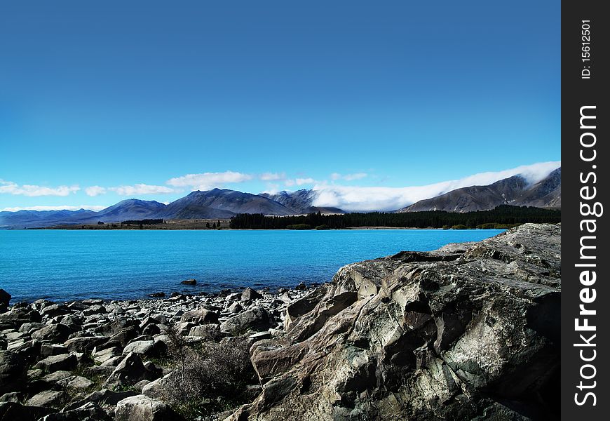 Lake scene with a rocky shoreline and mountains in the background