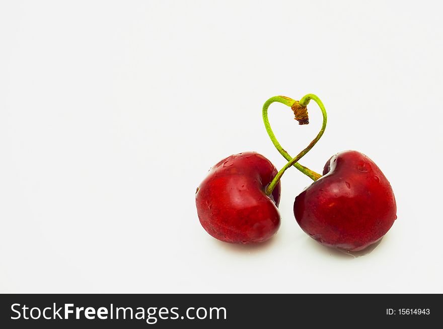 Pair of cherries were weaved by shanks in the form of heart isolated. Pair of cherries were weaved by shanks in the form of heart isolated