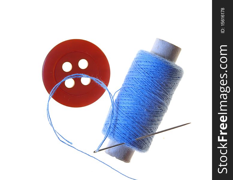 Spool with blue threads and needle and red button. Spool with blue threads and needle and red button