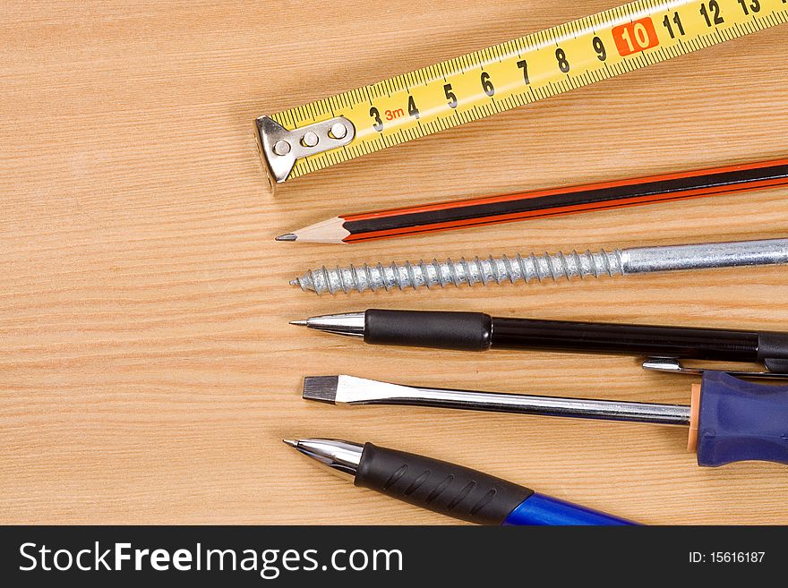 Pen, pencil and tape measure on wood table