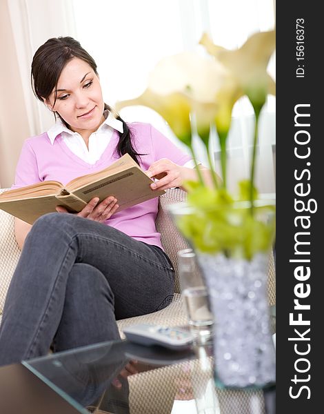 Young brunette woman reading book at home