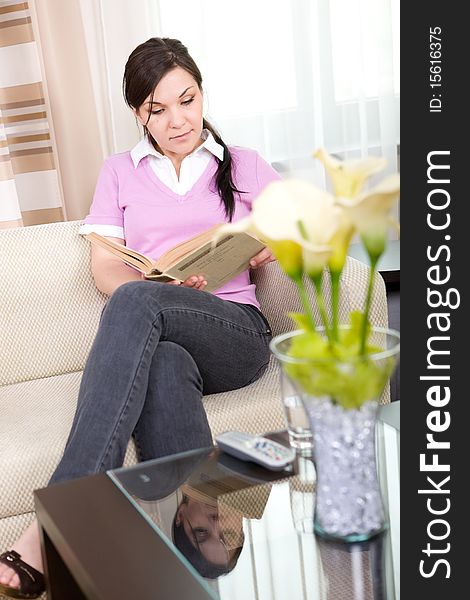 Young brunette woman reading book at home