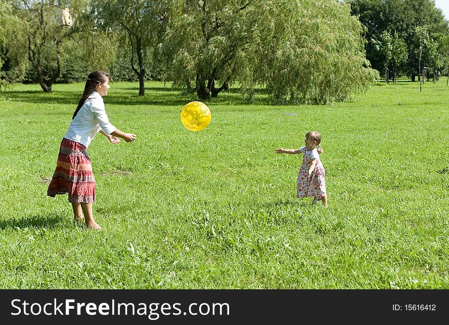 Mother and daughter playing ball on meadow. Mother and daughter playing ball on meadow
