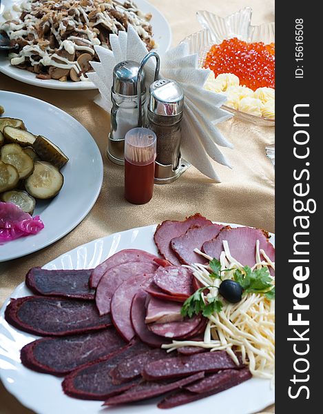 Tableware, paper napkins, salt, spices and appetizer on a table. Tableware, paper napkins, salt, spices and appetizer on a table.