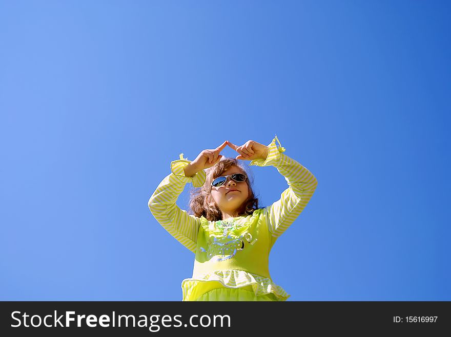 The girl in sun glasses draws in the dark blue sky fingers having lifted upwards hands. The girl in sun glasses draws in the dark blue sky fingers having lifted upwards hands