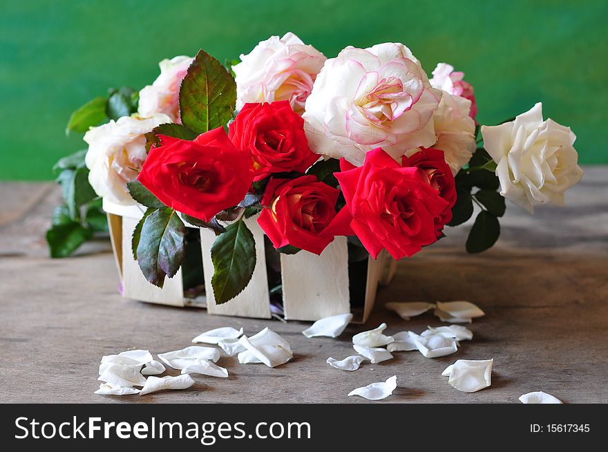 red and white roses are in a small basket