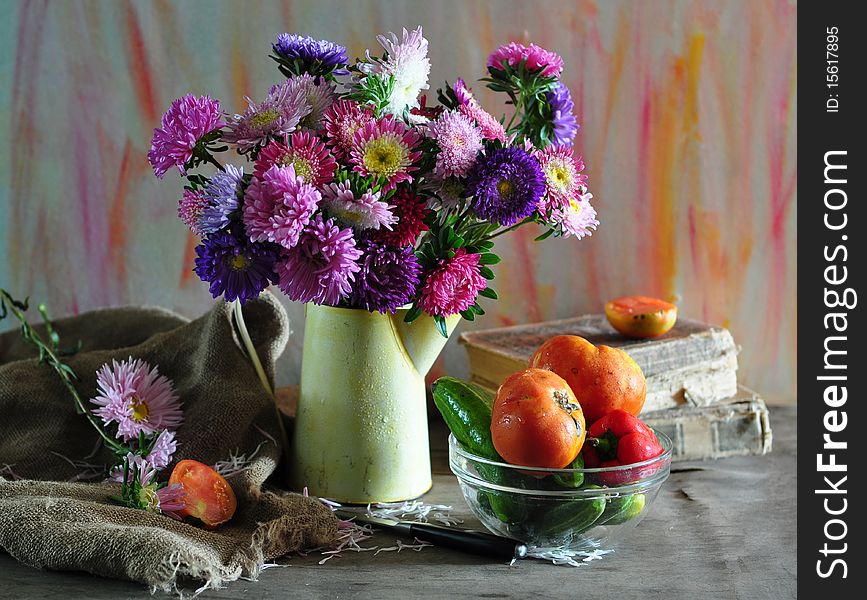 Bouquet of asters and dish with vegetables on an old table. Bouquet of asters and dish with vegetables on an old table