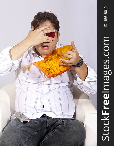 A young man watching a movie in 3D, with stylish 3D glasses and eating popcorn. A young man watching a movie in 3D, with stylish 3D glasses and eating popcorn.