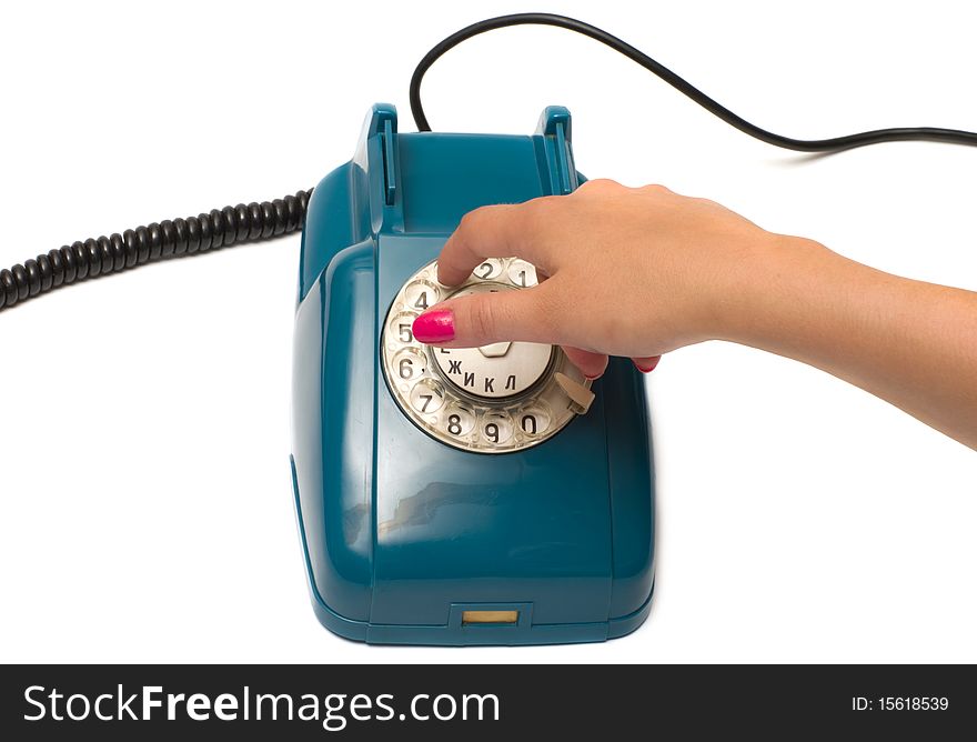 Ladies hand dials the number on the old phone isolated on a white background. Ladies hand dials the number on the old phone isolated on a white background.