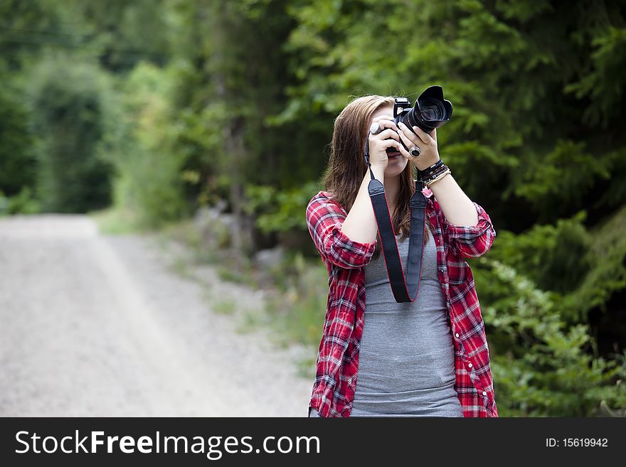 Teenage girl holding a camera shooting apicture outdoors. Teenage girl holding a camera shooting apicture outdoors