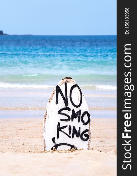 No Smoking warning sign on white surfboard at the beach in summer, concept of sea environmantal protection design, copy space