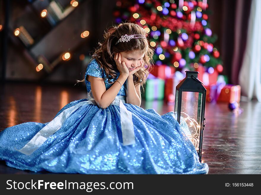 Cute little girl laying on flor with bright christmas garland in her hair. Christmas portrait, cozy style. Top view