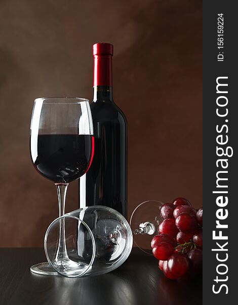 Grapes, bottle and glass with wine against brown background