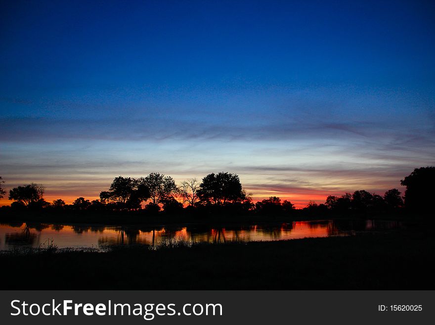 Blue And Red Sunset Over River With Hippos