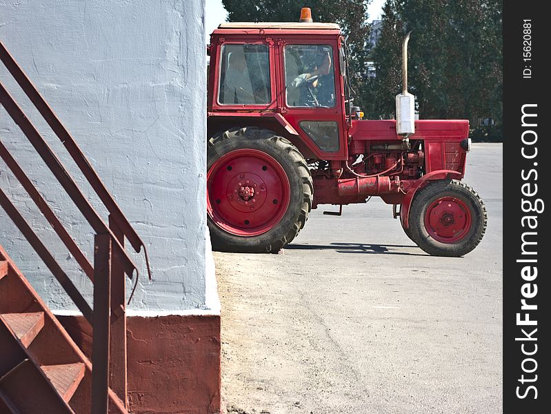 Red tractor resting in a white wall