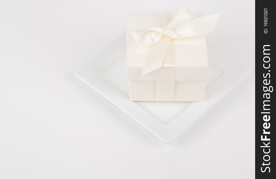 Small cream colored favor box on white plate and background. Small cream colored favor box on white plate and background