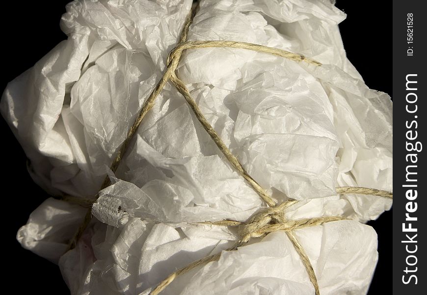 Close-up of clumsy parcel wrapped in crumpled paper and tied with coarse string. Example of insecure wrapping for shipping. Close-up of clumsy parcel wrapped in crumpled paper and tied with coarse string. Example of insecure wrapping for shipping.