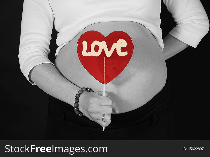 Pregnant woman keeping the red lillipop with the love inscription