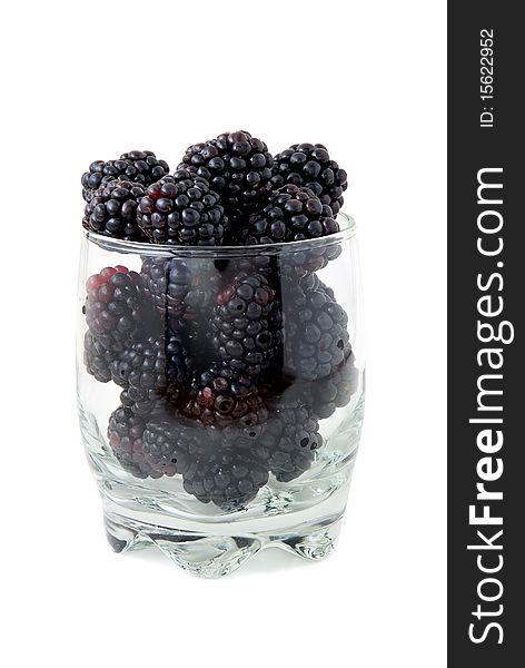 Blackberries in a glass are photographed on a white background
