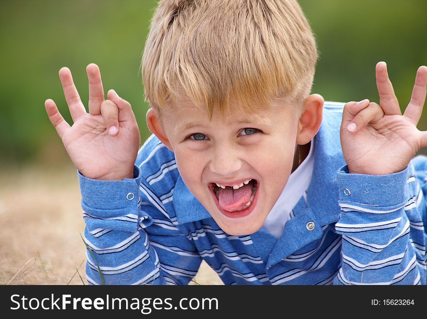 Boy builds a merry faces against the backdrop of green meadows. Boy builds a merry faces against the backdrop of green meadows