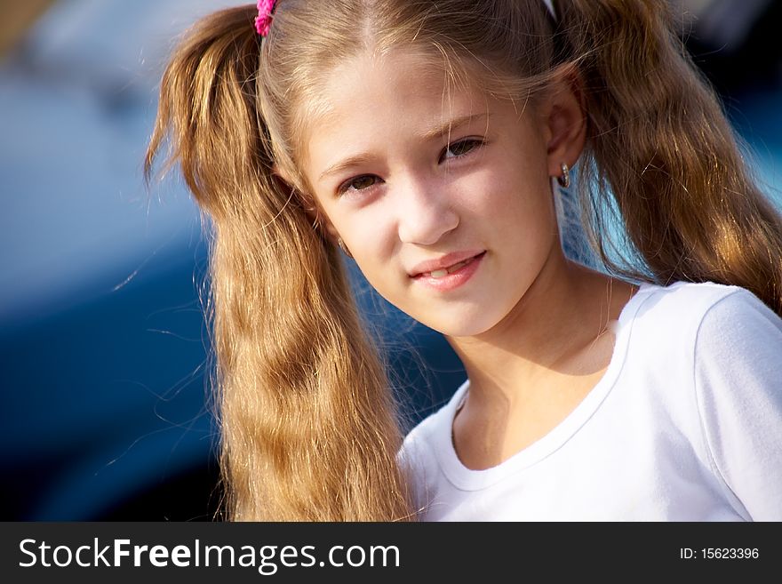 Portrait of little girl with long hair,smiling at the camera the blue