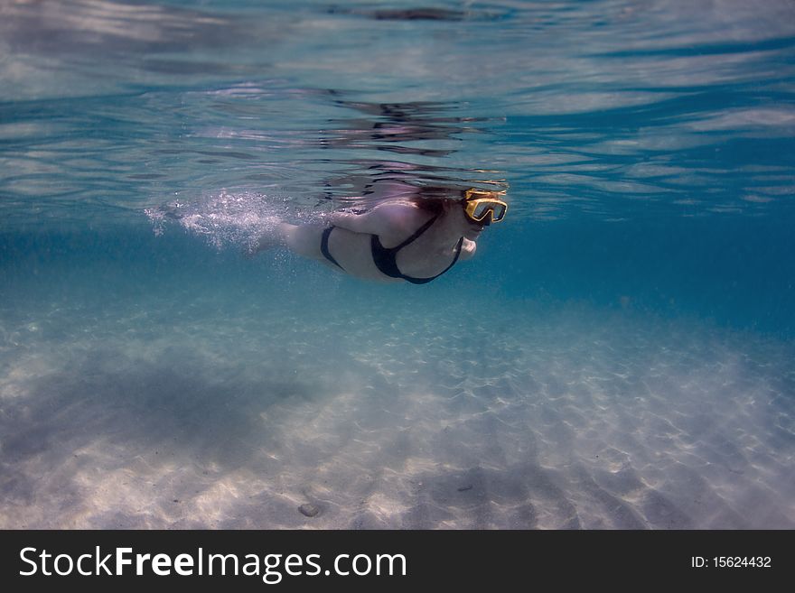 Woman swimming at the surface with a mask, over white sand. Woman swimming at the surface with a mask, over white sand