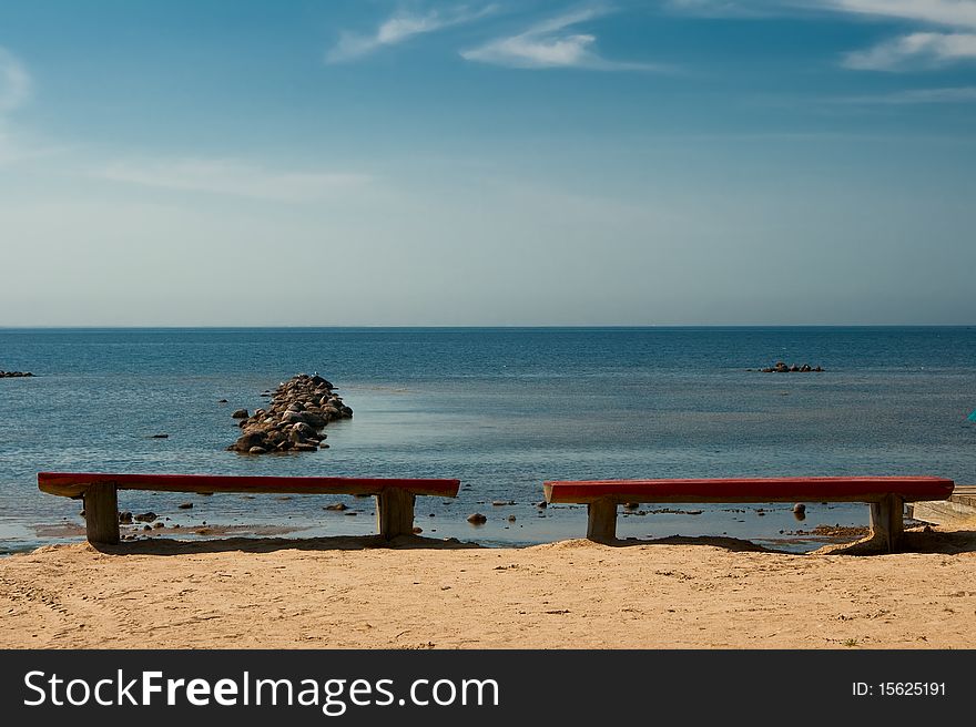 Two empty benches on the beach.