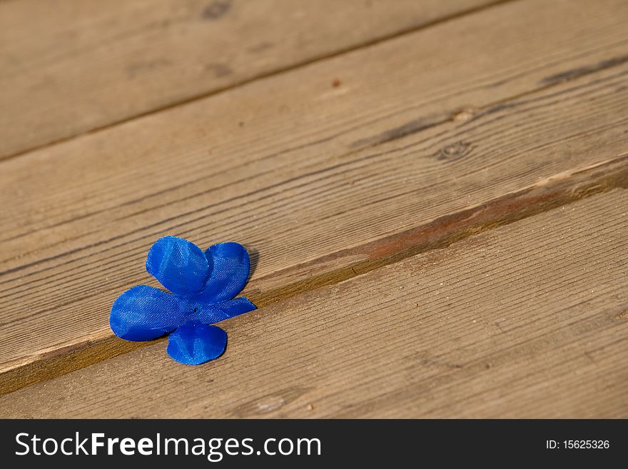 Blue fabric artificial flower on the background of the wooden floor. Blue fabric artificial flower on the background of the wooden floor.