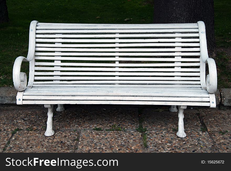 Old cast metal and wooden bench in front of the green grass and bushes. Old cast metal and wooden bench in front of the green grass and bushes