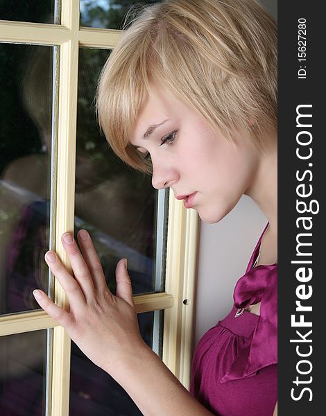 Beautiful blond female leaning against a door, expressing sadness and loneliness. Beautiful blond female leaning against a door, expressing sadness and loneliness
