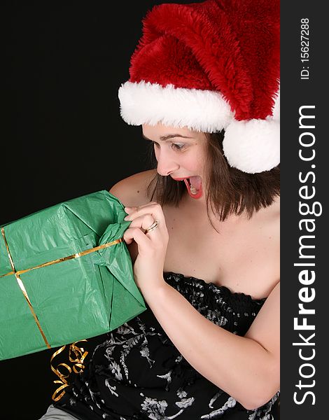 Beautiful brunette female wearing a christmas hat opening gifts. Beautiful brunette female wearing a christmas hat opening gifts