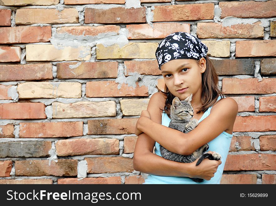 Teenage girl outdoor portrait with cat in arms over brick wall. Teenage girl outdoor portrait with cat in arms over brick wall