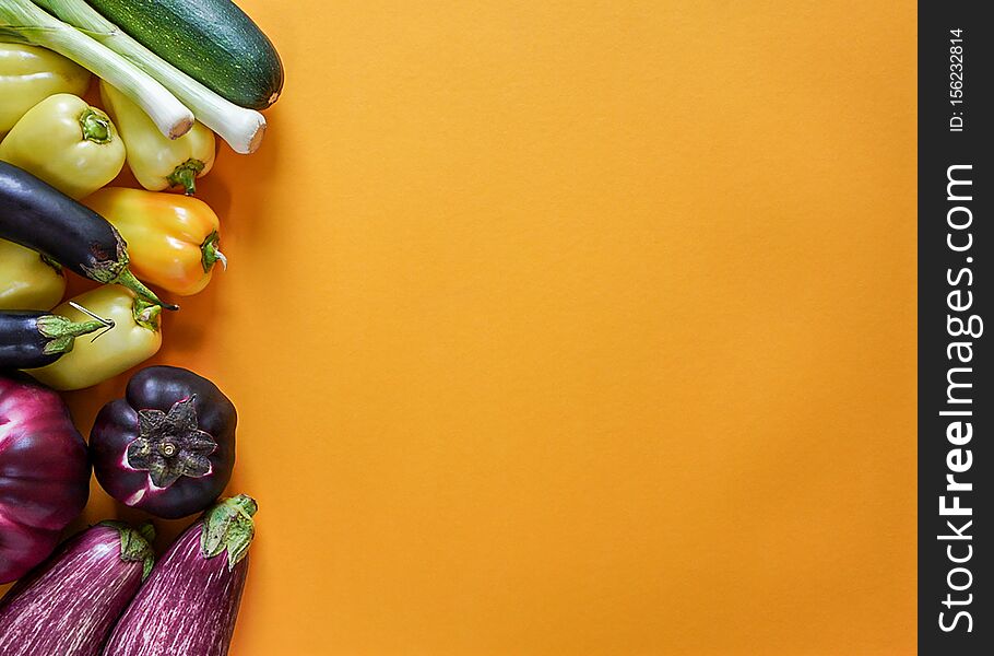 Seasonal vegetables from the garden of orange, green, yellow and purple colors lie freely on a yellow background, top view, copy space, horizontal frame. Seasonal vegetables from the garden of orange, green, yellow and purple colors lie freely on a yellow background, top view, copy space, horizontal frame