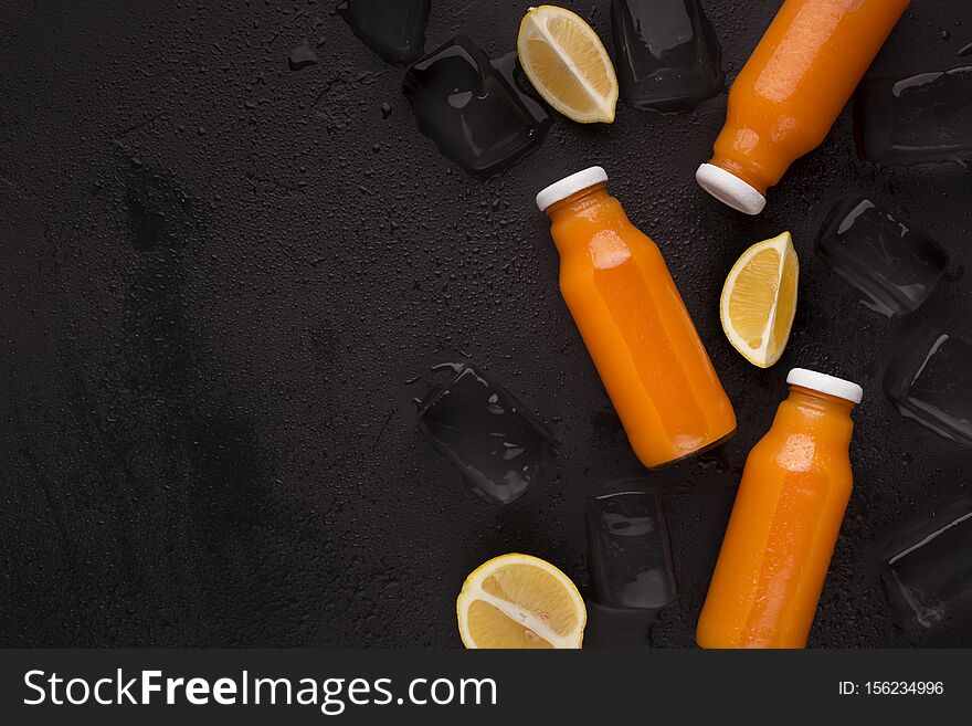 Orange fresh blended detox cocktail on black background with lemon slices and ice cubes