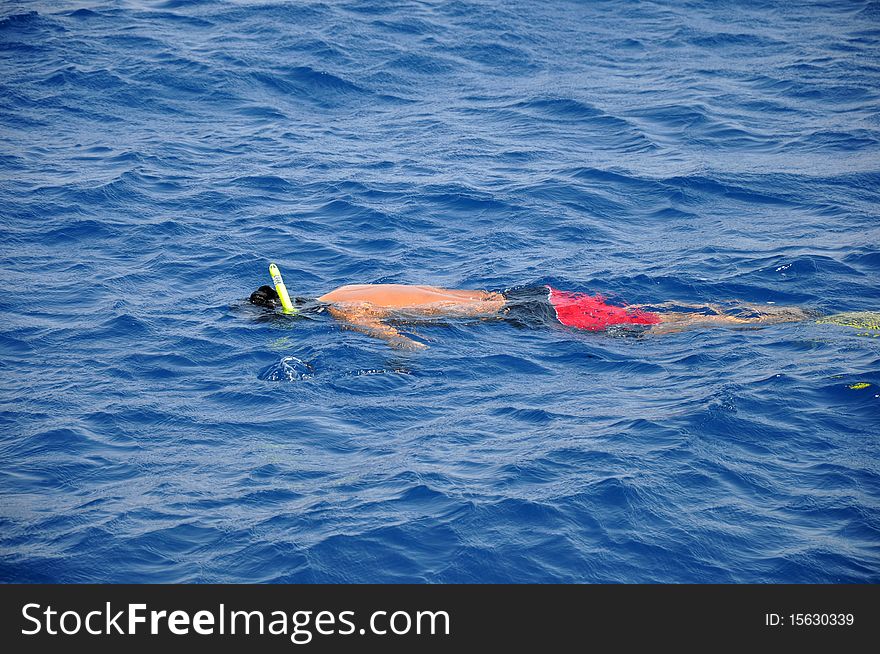 A man snorkeling in the blue sea